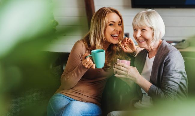 a couple of women sitting on a couch and smiling at the camera